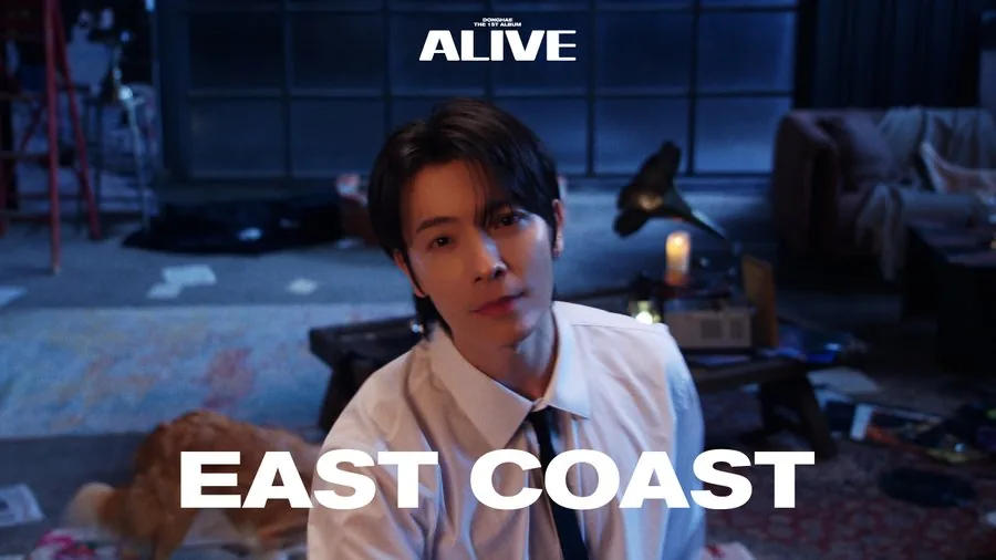 Still from the East Coast music video — DONGHAE in a warmly lit, dim apartment set