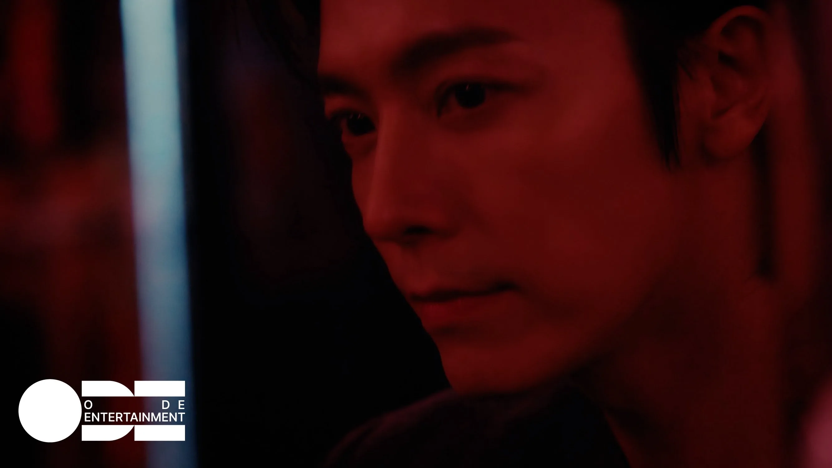 Still from the 해 떴네 music video, DONGHAE in deep red cinematic light with cold blue neon